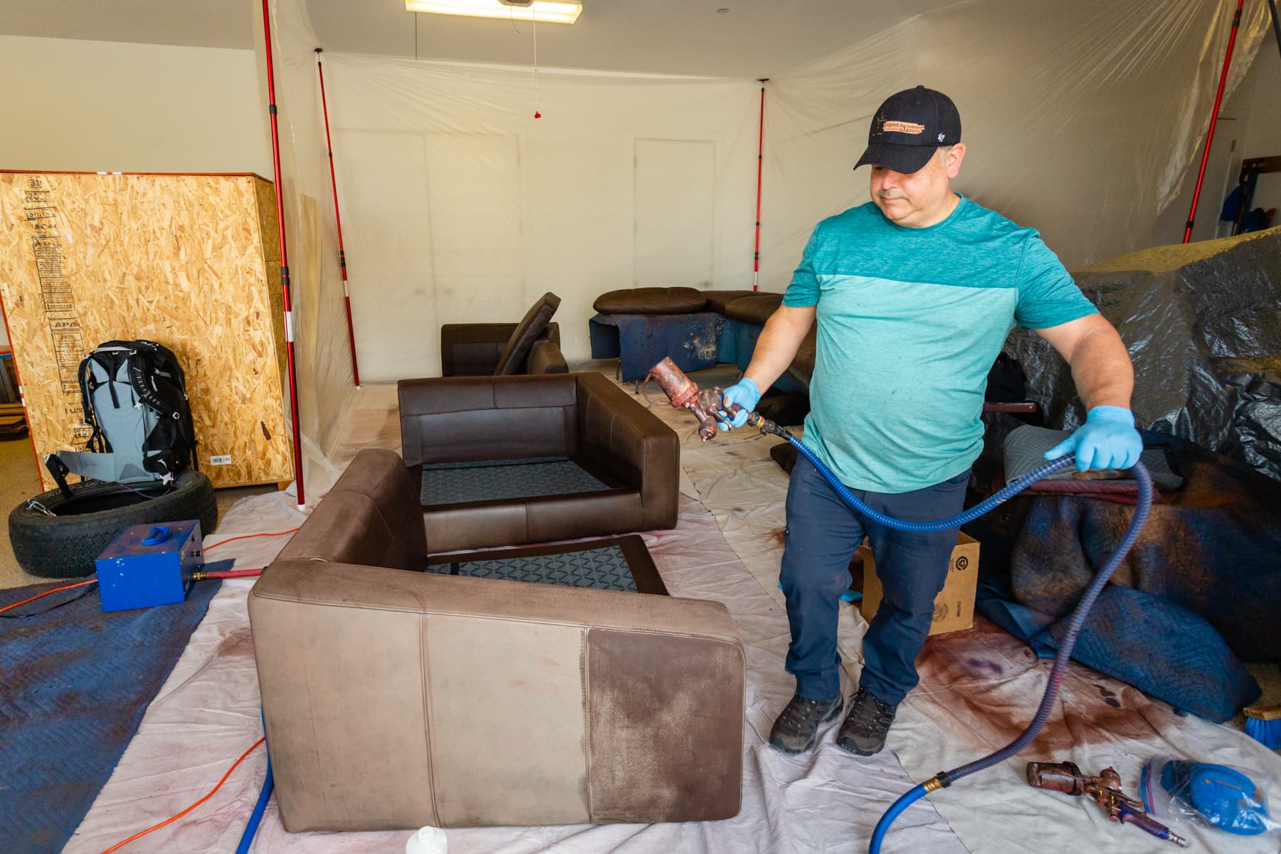 Technician working among several leather seating pieces in a workshop
