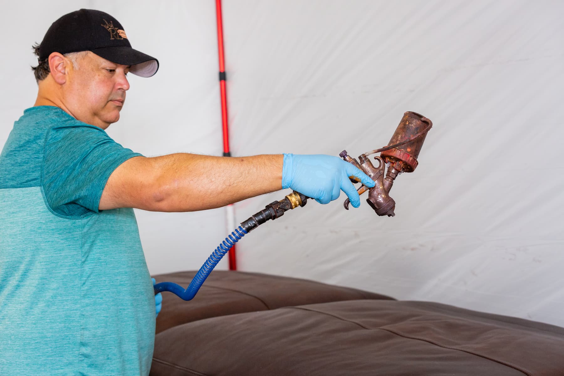 Michael applying finish to leather furniture with spray equipment