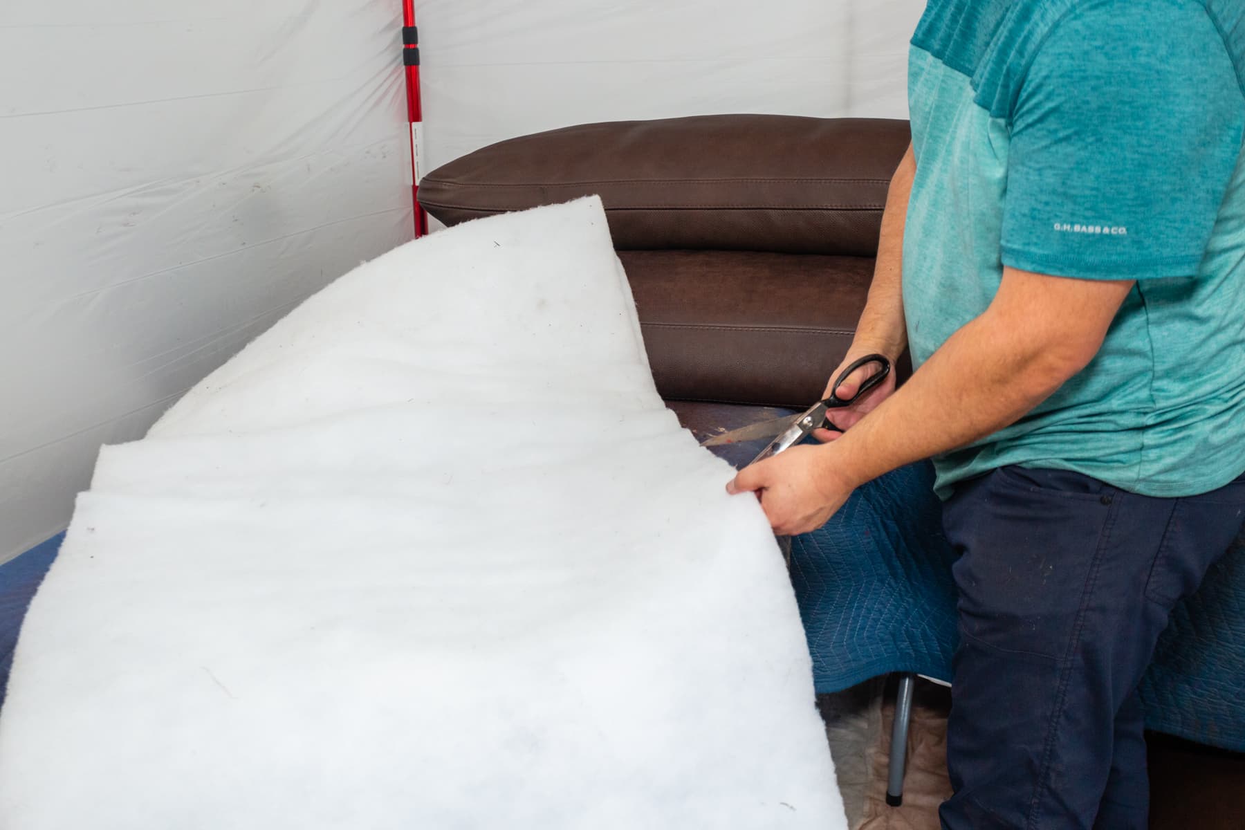 Technician cutting a white padding layer beside sectional seating